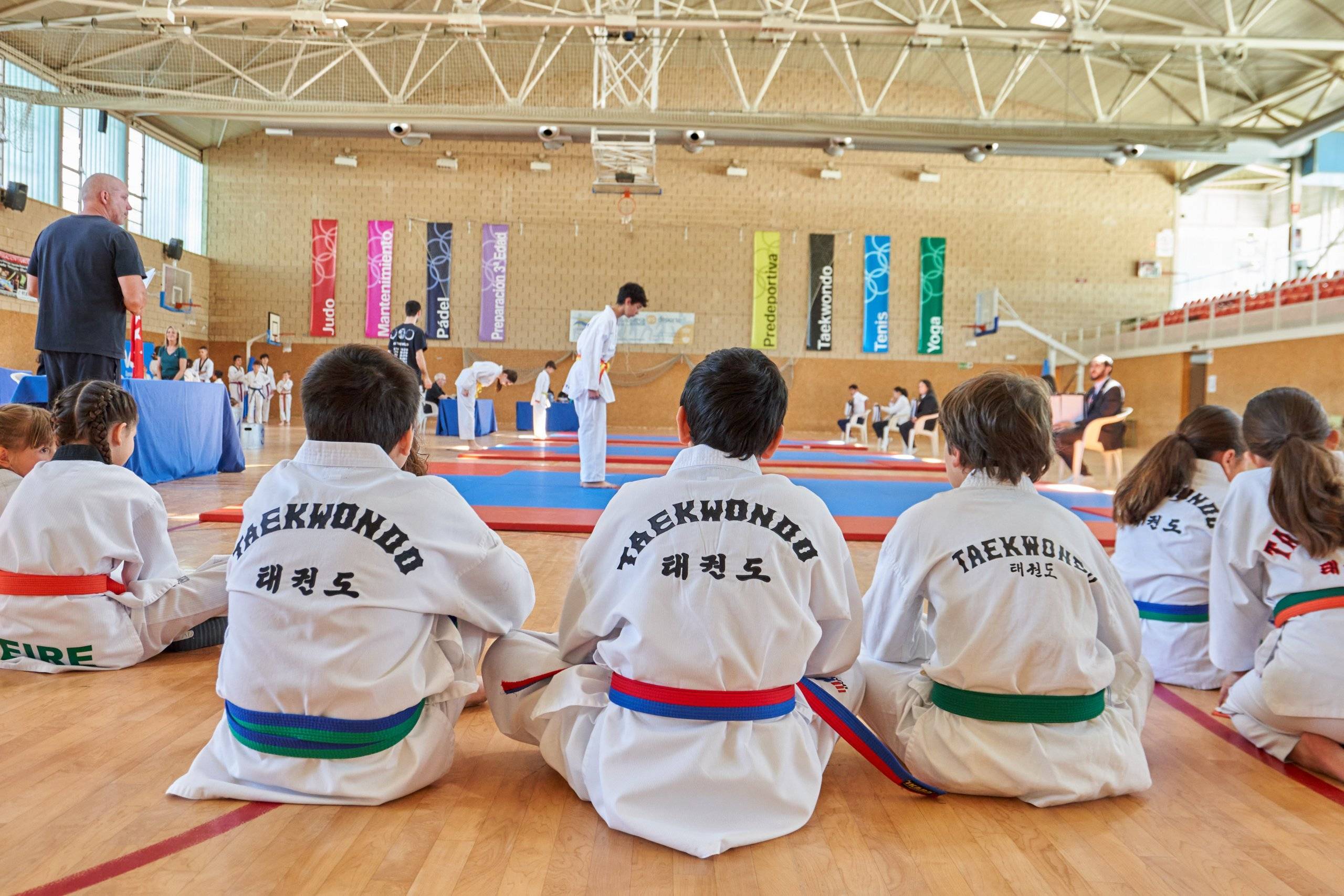 Participantes del Campeonato de Taekwondo mirando a otros deportistas mientras realizan su ejercicio.